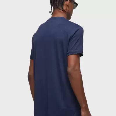 Homem de costas com t-shirt azul escura de manga curta e calças azuis