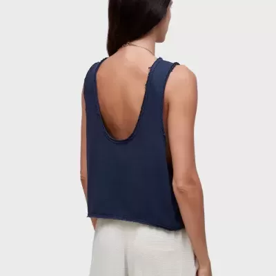 Top azul escuro sem mangas com decote baixo nas costas e calças largas brancas.