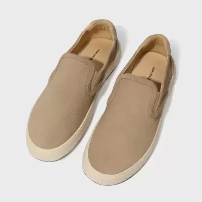 Sapatilhas slip-on bege com sola branca sobre fundo branco