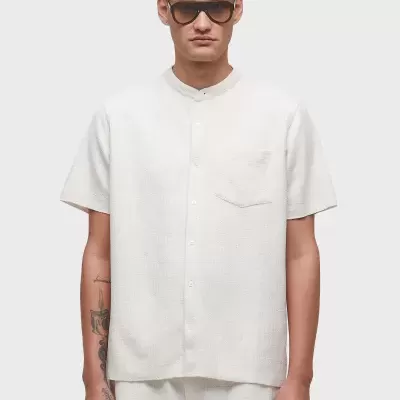 Homem com camisa branca de manga curta e óculos escuros