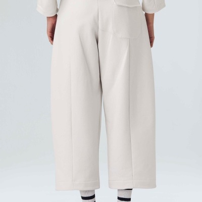 Calças largas cinza claro com bolso traseiro, usadas com meias e sapatos desportivos laranja.