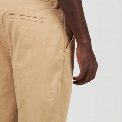Calças bege de tecido liso com bolsos, vista lateral direita.