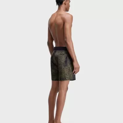 Homem de costas a usar calções de banho com padrão de folhas verdes e pretas