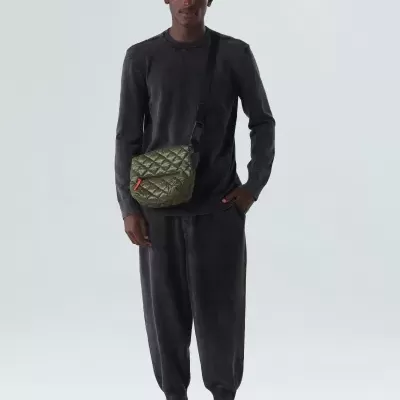 Homem com roupa preta e bolsa de ombro acolchoada verde