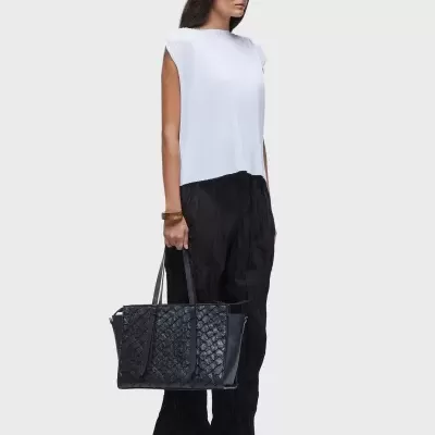 Mulher de pé com mala preta e roupa branca e preta