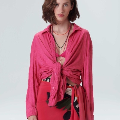 Mulher vestindo blusa rosa amarrada e saia estampada colorida