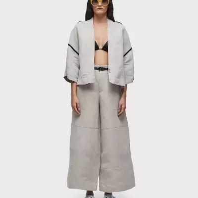 Mulher a usar conjunto feminino bege claro com top preto, óculos amarelos e sandálias brancas