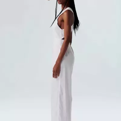 Mulher de perfil com vestido branco, chapéu de palha e sandálias brancas