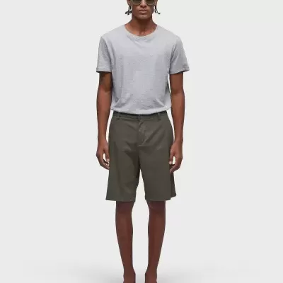 Homem com t-shirt cinzenta, calções verde-oliva, chinelos castanhos e óculos de sol verdes