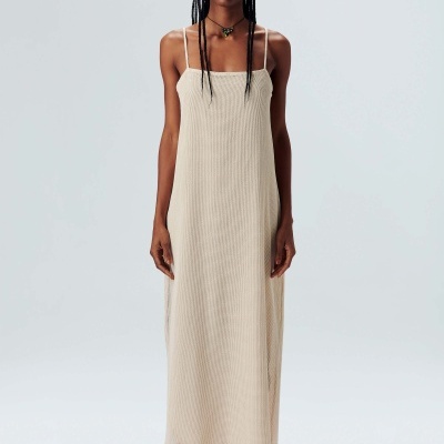 Vestido longo bege em tecido canelado com alças finas, meias vermelhas e sapatos neutros