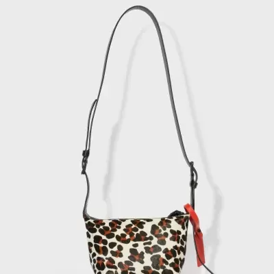 Mala pequena animal print com alça preta e etiqueta vermelha