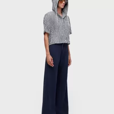 Pessoa com camisa curta às riscas preta e branca com capuz e calças largas azuis escuras