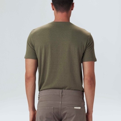 Homem visto de costas vestindo camisola verde-oliva de manga curta e calças castanhas