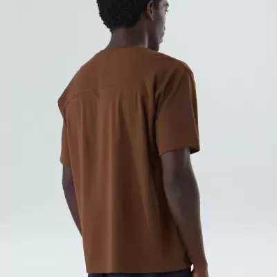 Homem vista de costas com t-shirt castanha e calças azul-escuras