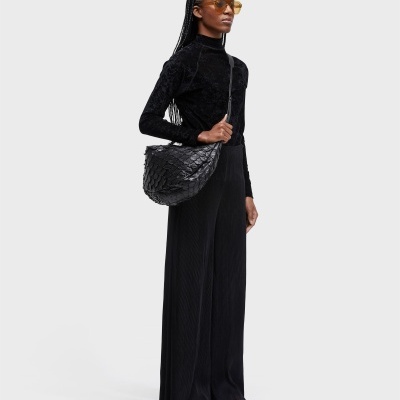 Mulher de pé vestindo conjunto preto e bolsa preta texturizada