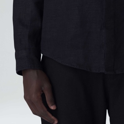 Parte inferior de camisa preta e parte superior de calças pretas com textura visível.