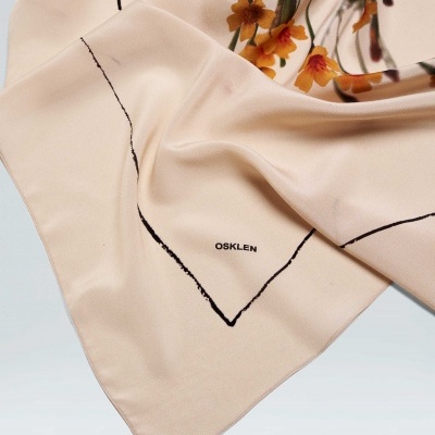 Lenço bege com estampado floral e linhas pretas, com a marca OSKLEN