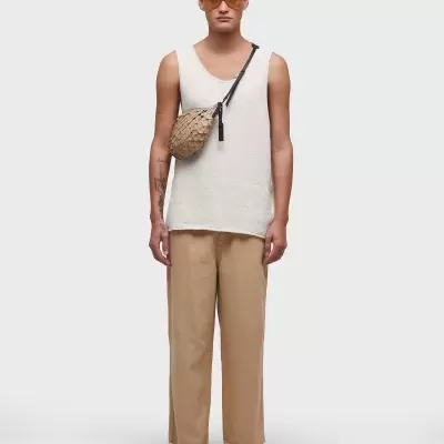 Homem com roupa casual e mala tiracolo em fundo cinza claro