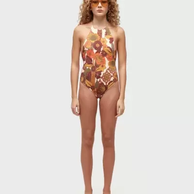 Maiô floral multicolor com decote halter usado por mulher com óculos laranja e sandálias bege