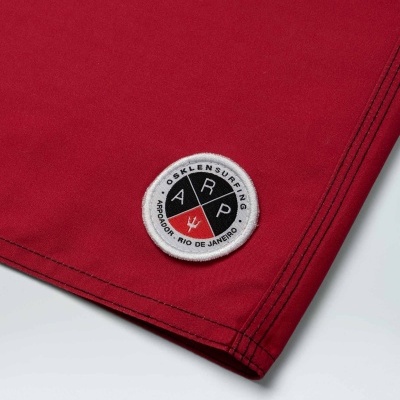 Peça de roupa vermelha com emblema OSKLENSURFING perto da barra