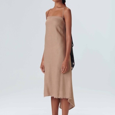 Modelo com vestido bege comprido e alças finas, sandálias brancas e lenço preto com bolinhas brancas na cabeça