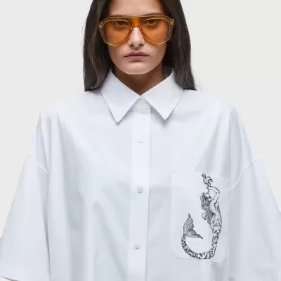 Camisa branca oversized com bolso e estampa de sereia e óculos de sol amarelos