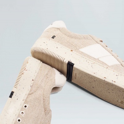 Ténis bege em tecido com sola branca e detalhes brancos sobre fundo claro