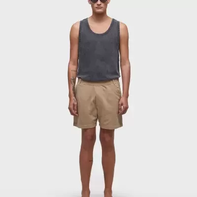 Modelo masculino com regata preta, calções bege e chinelos pretos.