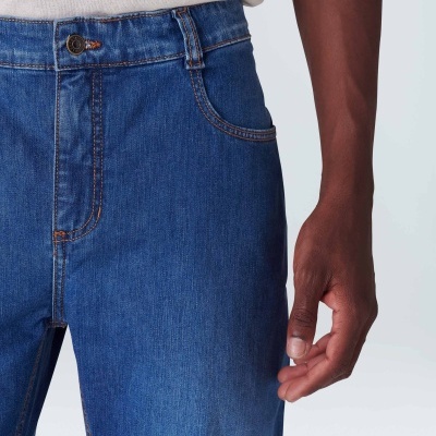 Pessoa com jeans azul e t-shirt creme, fundo claro