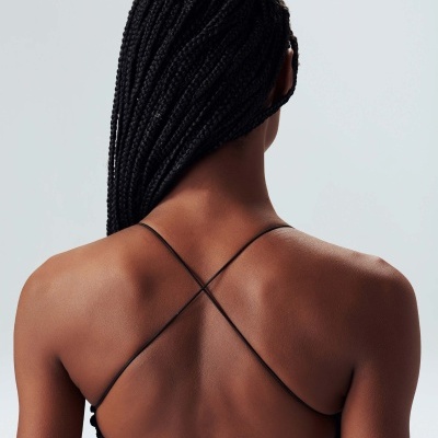 Costas de mulher com top preto de alças cruzadas e cabelo trançado