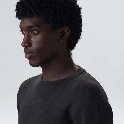 Homem com camisola preta de manga comprida e decote redondo