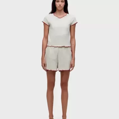 Conjunto de pijama bege com bordas vermelhas e sapatos castanhos.