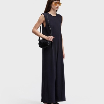 Mulher com vestido preto e acessórios pretos e óculos com lentes amarelas.