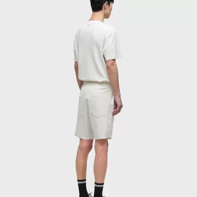 Homem de costas com roupa casual bege e ténis em estúdio com fundo cinzento