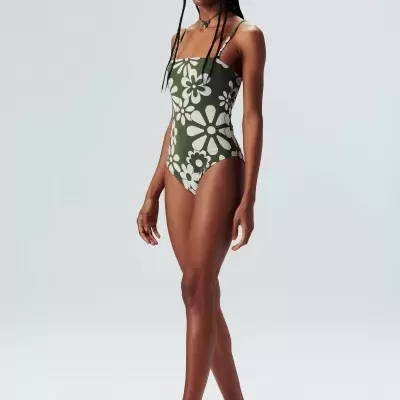 Mulher a usar fato de banho verde com flores brancas e acessórios