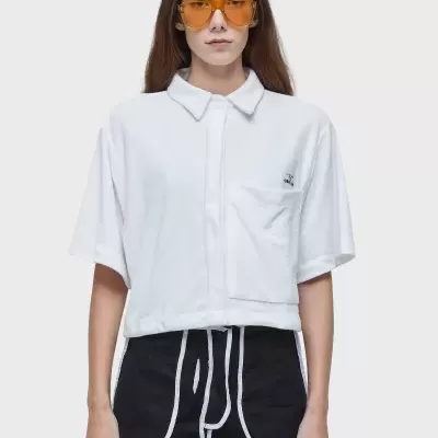 Mulher com camisa branca e calções pretos com óculos de sol amarelos