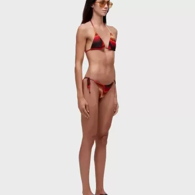 Modelo com biquíni colorido ondulado, óculos de sol amarelos e sandálias pretas