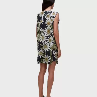 Vestido com padrão de margaridas brancas e amarelas sobre fundo preto, sem mangas e comprido até aos joelhos.