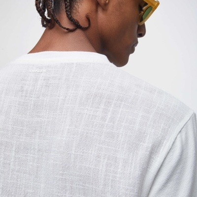 Homem visto de costas com camisola branca texturizada e óculos de sol amarelos