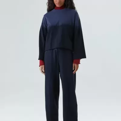 Mulher com conjunto azul escuro e camisa vermelha por baixo, calçado colorido floral