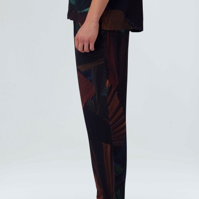 Pessoa de pé com calças estampadas e sapatilhas bege sobre fundo branco