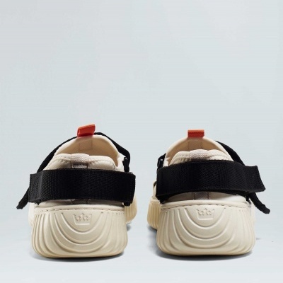 Sandálias desportivas bege com sola branca e tiras pretas vistas de trás.