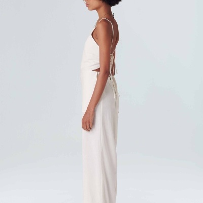 Mulher com conjunto branco, top de alças finas e calças largas