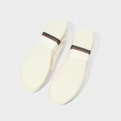 Solados de sapatos em borracha branca com faixa preta e castanha.