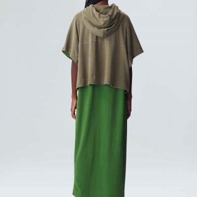 Mulher de costas usando poncho verde-oliva com capuz e vestido longo verde