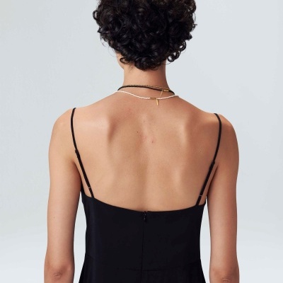 Vestido preto de alças finas visto de costas, usado por pessoa com cabelo curto encaracolado