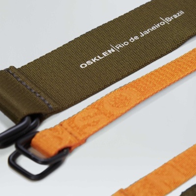 Correia de tecido verde oliva com fivela e texto OSKLEN e correias laranjas com fivelas