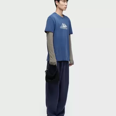 Homem de perfil a vestir roupa casual azul e cinzenta