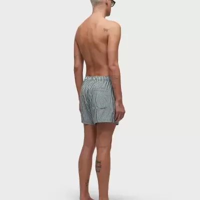 Homem de costas com calções de banho cinza às riscas e chinelos pretos