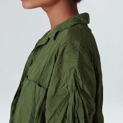 Camisa ou casaco verde com tecido amassado e gola clássica vista de perfil